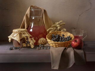 An autumn still life in calm tones. A jug on a table, dry branches, nuts, and grapes.