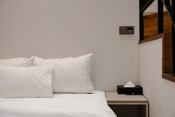 Cozy bedroom interior featuring soft white bedding and a modern bedside table.