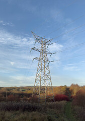 Electric Power Transmission Tower Over Quiet Countryside Under Blue Sky During Golden Hour