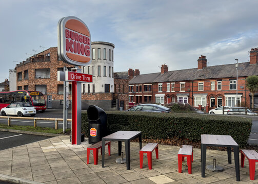 crewe cheshire united kingdom 12/05/2025 Burger King Drive-Thru Sign, Outdoor Seating, and Urban Street Scene with Red Tables