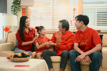 Young girl gives oranges to her grandfather and receives a red envelope, Chinese New Year