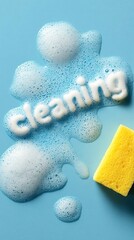 The word "cleaning" written in thick soap foam and a yellow sponge on a blue background. Banner with copy space. Cleaning service and premises maintenance concept vertical photo.