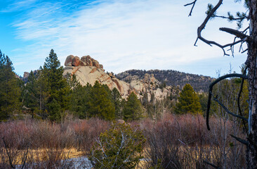 Granite hills rising above wet meadow and pine forest at Vedauwoo Recreation Area in Wyoming beneath expansive skies showcasing rugged wilderness