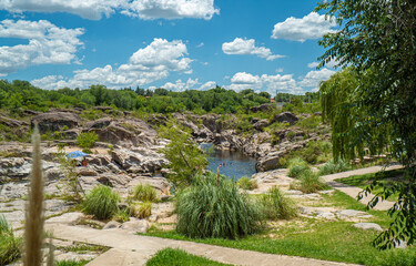 A path leads through a grassy area with a small stream