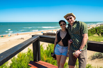 A man and a woman are posing for a picture on a beach