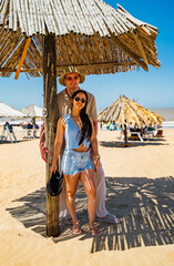 A man and a woman are standing under a bamboo umbrella