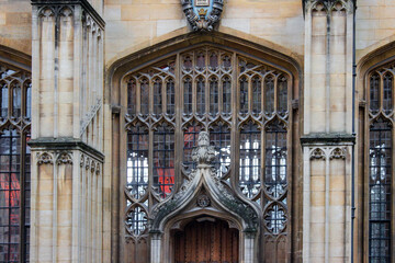 Naklejka premium The ornate Gothic entrance to the Divinity School in Oxford. It features intricate stonework and tall stained-glass windows, a historic site known for its use as a Harry Potter filming location.