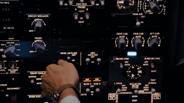 Close-up of airplane pilot operating controls in cockpit at night