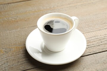 Cup of aromatic coffee on wooden table, closeup