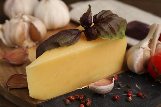 Dairy product. Piece of cheese, basil, peppercorns and garlic on table, closeup - Powered by Adobe