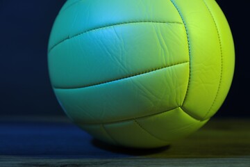 One volleyball ball on floor against dark background in color lights, closeup
