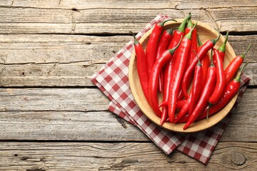 Ripe red chili peppers on wooden table, top view. Space for text