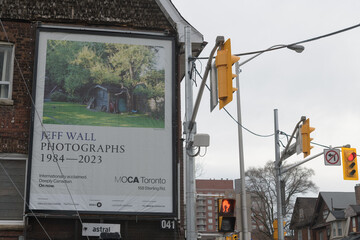 Naklejka premium roadside billboard advertisement for a Jeff Wall exhibition at MOCA spotted at northeast corner of Perth Ave & Bloor St W in Toronto (Lucky Convenience Convenience