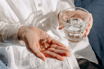 Person Holding Pills And Glass Of Water In Calm Home Setting For Health And Wellness
