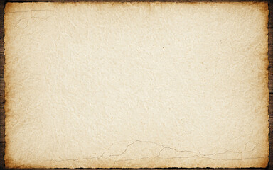 old weathered antique parchment paper with ragged torn edges and dark cracks on brown wood surface background with vintage historic document texture history heritage.