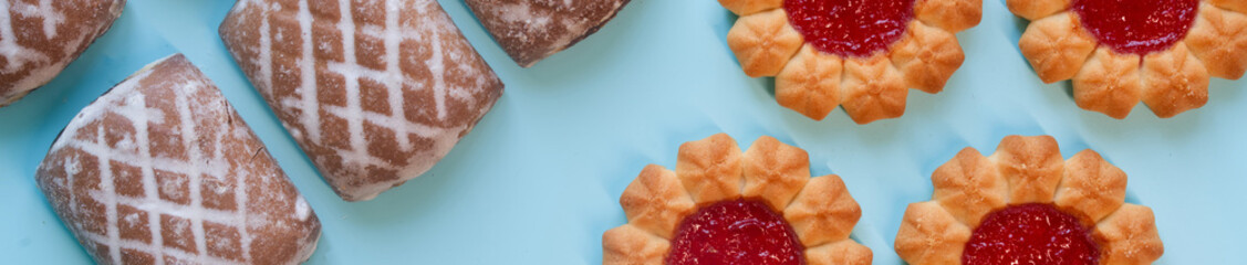 Creative border design of sweet pastry. Sugar biscuits with berry jam and iced gingerbread cakes on...