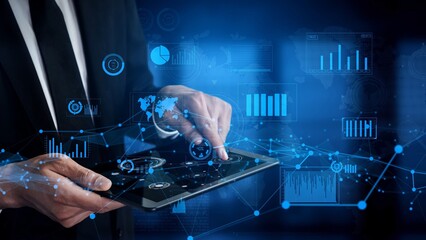 A businessman uses a tablet for data analysis in a modern office setting, surrounded by digital graphs and charts that highlight technology and innovation in business. Xenic