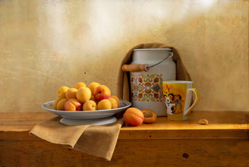 Still life with a plate of apricots, a can, and a glass in yellow and orange tones