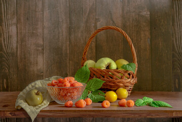 A delicious still life with orange raspberries and green apples in a basket