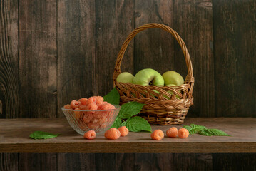 A delicious still life with orange raspberries and green apples in a basket
