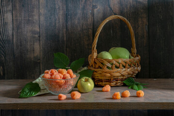 A delicious still life with orange raspberries and green apples in a basket