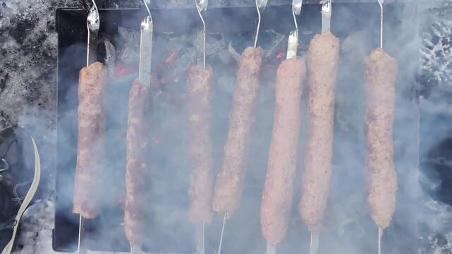 Lula kebabs are skewered on a grill and roasted over hot coals. A winter setting, outdoors.