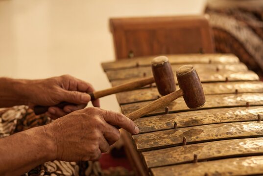 Hands play wooden xylophone with mallets in traditional setting during music practice in local venue at afternoon - Powered by Adobe