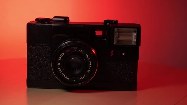 35mm film camera rotating in red room, darkroom. Old film camera, vintage analog in classic retro Analog photography.