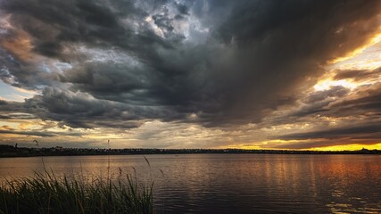 Storm clouds over sunset lake