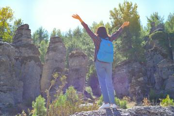 A woman tourist with a backpack on her back walks through the ancient city of Selga, admiring the wonderful nature and wonderful rocks. Turkey, Antalya