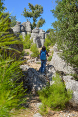A woman tourist with a backpack on her back walks through the ancient city of Selga, admiring the wonderful nature and wonderful rocks. Turkey, Antalya