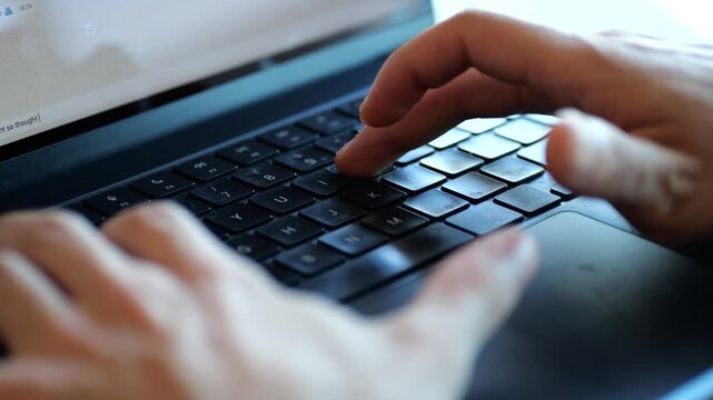 Hands typing on laptop with bandaged finger
