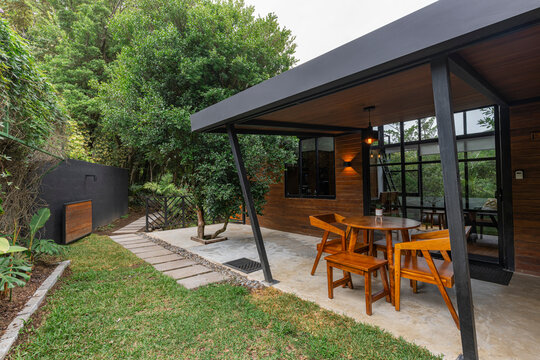 Modern rustic cabin patio with wooden dining set and garden path
