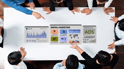 A group of professionals engages in a dynamic meeting focusing on digital marketing strategies, analyzing data and visuals on a collaborative workspace. Raster