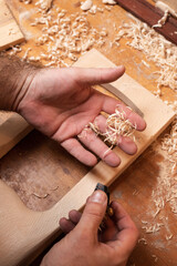 The master works with a mini plane, a lot of small shavings