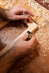 The master is whittling with a mini plane, a lot of small shavings