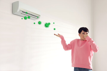 Woman covering her nose because of bad smell from air conditioner in room. Bacteria flying from...