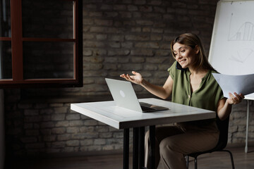 Busy businesswoman talking on the phone while working on laptop in the office