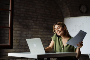 Busy businesswoman talking on the phone while working on laptop in the office