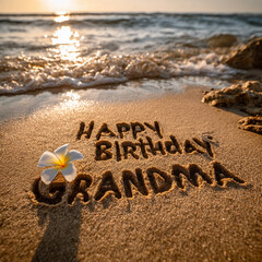Happy Birthday Grandma Bold Handwritten in Wet Sand with White Jasmine Flower and Golden Hour Sun, Clean Beach with Gentle Ocean Foam &ndash; perfect for birthday greetings