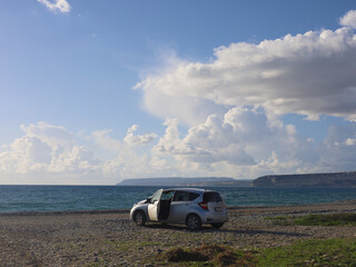 Car parked by the ocean under a cloudy sky