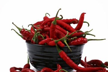 Fresh red chili peppers arranged in a black bowl isolated on white background, vibrant spicy food...