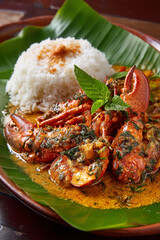 A freshly cooked plate of Langouste (lobster) with coconut gravy served alongside fragrant rice and green bananas.