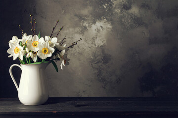 A bouquet of daffodils in jug, dark background , copy space