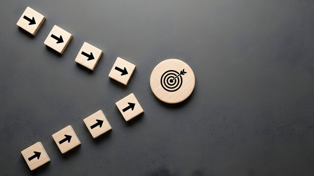Achieving your business goals requires a clear vision and strategy, as demonstrated by these wooden blocks pointing towards a target, indicating success.