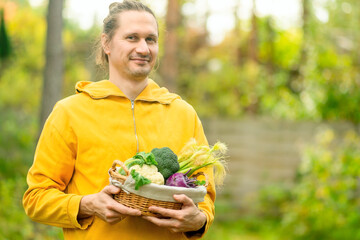 Close up of male farmer with basket full of cauliflower, kohlrabi, broccoli, and corn. Fresh vegetables, healthy nutrition, and harvest pride.