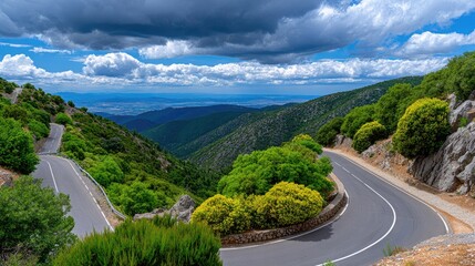 Scenic winding road through lush green mountains under a dramatic cloudy sky, offering breathtaking views of the landscape below
