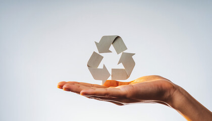 Hand holding paper recycling symbol on gray background