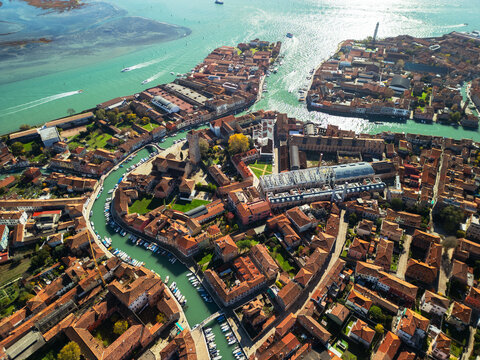 Aerial view of Murano island with traditional red roofs and canals. Cinematic drone panorama of the Venetian Lagoon, Italy.