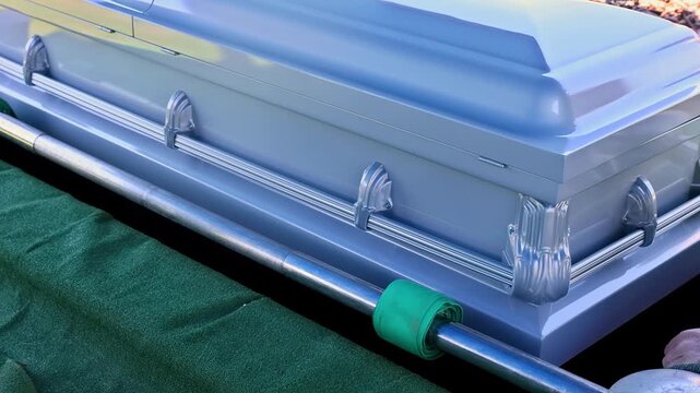 Coffin features decorative handles supporting it of funeral setup while maintaining focus on the casket details during burial ceremony